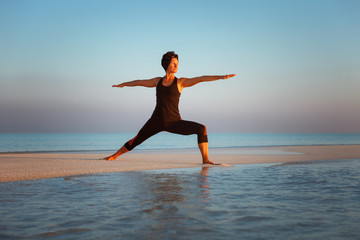 Fototapeta na wymiar young girl standing in yoga warrior asana on dreamlike beach on summer vacation