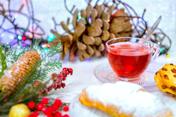 Christmas tea in glass Cup . composition with cookie, pine branches, cones on background of garlands on wooden table