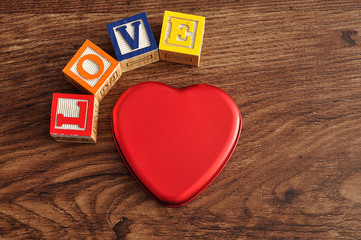Valentine's Day.Love Spelled with colorful alphabet blocks and a red heart shape tin
