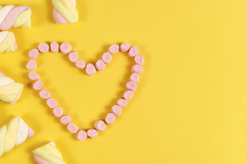 marshmallow sweets placed in heart shape.valentine's day and love concept on yellow background