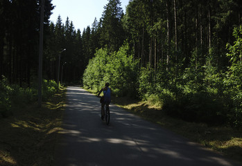 Healthy and happy cyclist woman riding fast a bicycle in a park