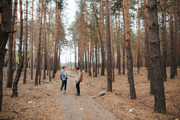 Halt. Travelers think over the route. Brutal men in warm hat with a backpack in the woods on a background of trees