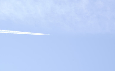 Flying airplane on the blue sky leaving white lines behind