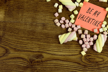 A sticker with Text: Be My Valentine decorated with marshmallow sweets. love concept on wooden background.