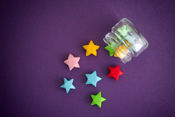 Colorful origami lucky stars spilling out of a jar