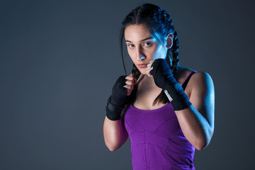 Female boxer makes a fight with a shadow, dark background with space for text. Strong and confident, she will be a champion.