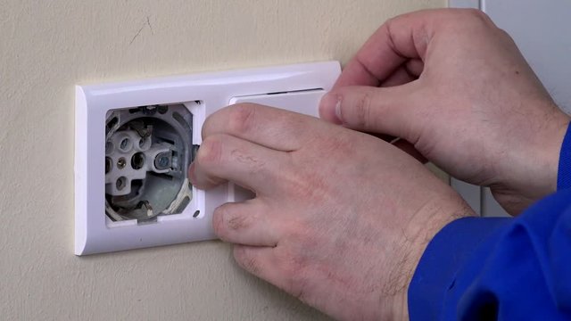 close up of hands with screwdriver install electrical socket on wall
