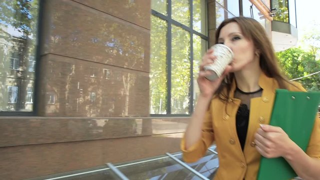 Business lady drinks street coffee during lunch and hurries to office. Business woman walking in business district with cup of coffee