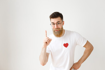 Clever young man with long thick beard raises fore finger as gets brilliant idea, wears round...