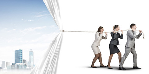 Young businesspeople working in collaboration and pulling white advertisement banner