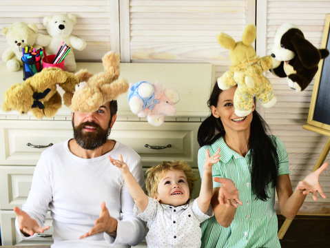 Mom, Dad And Boy Throw Toys Up On Wooden Background.