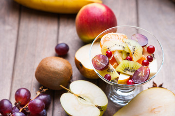 Fresh fruit salad and fruits on wooden table 