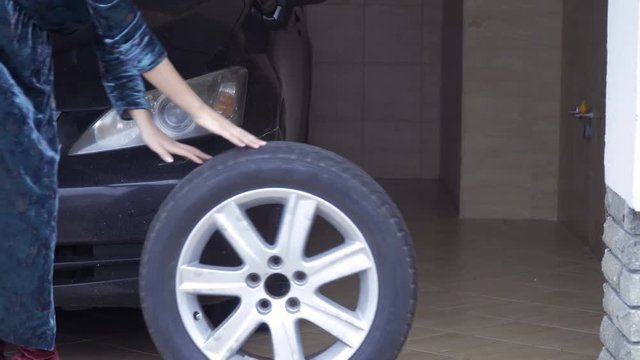 Woman rolls out the car spare wheel