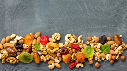 Fotobehang Various dried fruits and mix nuts on a gray stone or slate background.  The concept of the Jewish holiday Tu Bishvat. Flat lay, top view with copy space. © elena_hramowa