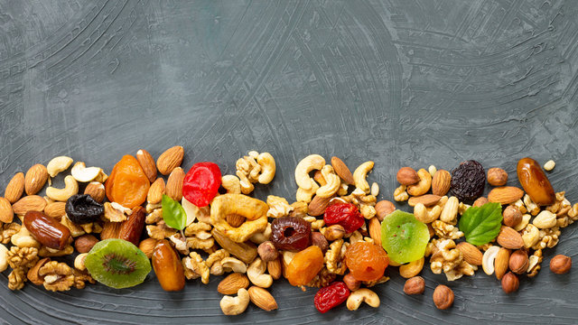 Various dried fruits and mix nuts on a gray stone or slate background.  The concept of the Jewish holiday Tu Bishvat. Flat lay, top view with copy space.