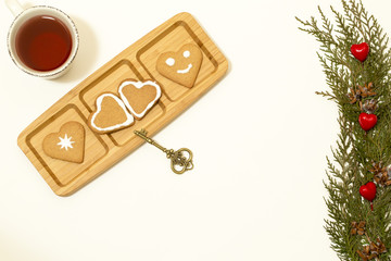 Valentines day concept: Cookies in heart shape symbolize Love decorated with glass of tea, old golden key and green pine branches isolated on white background. Top view. Macro, close up.