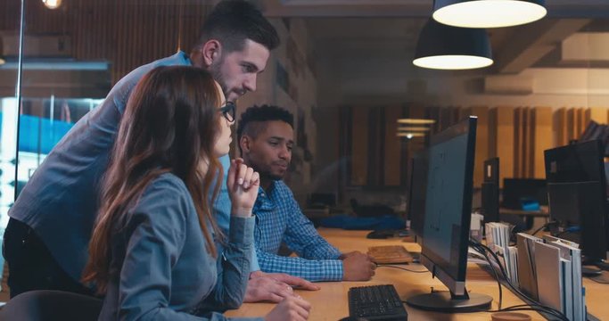 Diverse group of three multiracial colleagues professionals brainstorming together while discussing a project on computer screen. 4K UHD