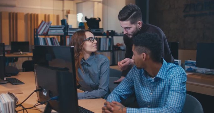 Diverse group of three multiracial colleagues professionals brainstorming together while discussing a project on computer screen. 4K UHD