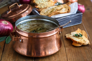 Traditional onion soup with cheese and croutons, colorful onions on background