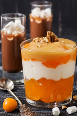 Delicious dessert layers of yogurt persimmon nuts. Dessert is served in a glass on a napkin with a...