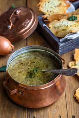 Close view of copper pot with onion soup and croutons