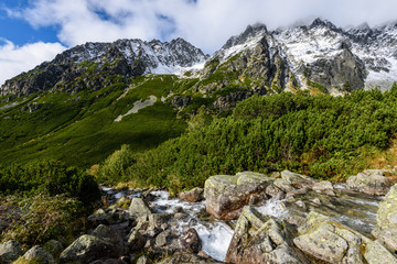large Waterfall from ravine in autumn, long exposure with mountains in background