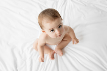 cute baby sitting on bed seen from above
