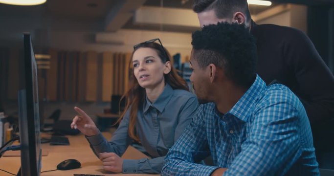 Diverse group of three multiracial colleagues professionals brainstorming together while discussing a project on computer screen. 4K UHD