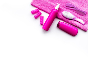 Basic hair care in bathroom. Comb, shampoo, spray, curlers, towel on white background top view copyspace