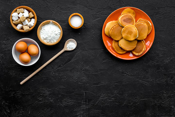 Make fluffy pancakes. Ingredients, cakes and toppings like nuts and honey on black background top view copyspace