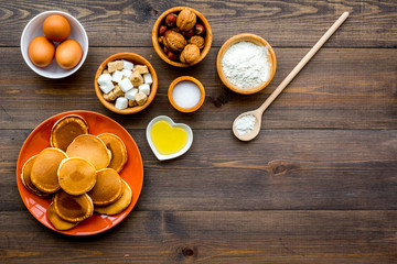 Make fluffy pancakes. Ingredients, cakes and toppings like nuts and honey on dark wooden background top view copyspace