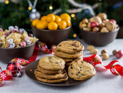 freshly baked chocolate chip cookies on a table with blurred christmas tree background.