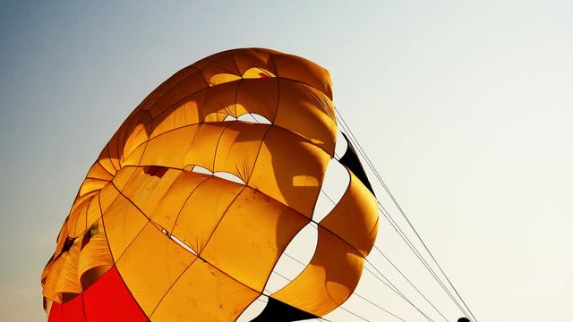 Parachute dome for parasail against the sky. It is illuminated by the rays of the setting sun. Water sports on the beach.