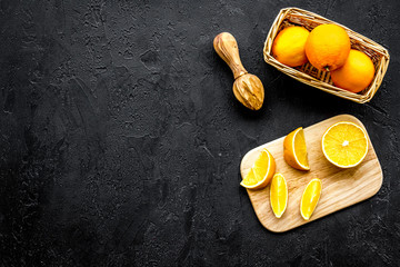 Squeeze juice from oranges. Juicer and slices of oranges on black background top view copyspace