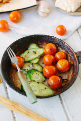 Roasted cherry tomatoes and cucumbers in frying pan.