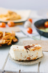 Big piece of tofu - vegan cheese, roasted. With vegetables and other food.