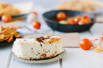 Big piece of tofu - vegan cheese, roasted. With vegetables and other food.