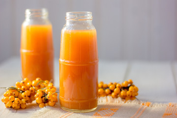 Healthy drink - sea buckthorn juice in a glass bottle over wooden table.