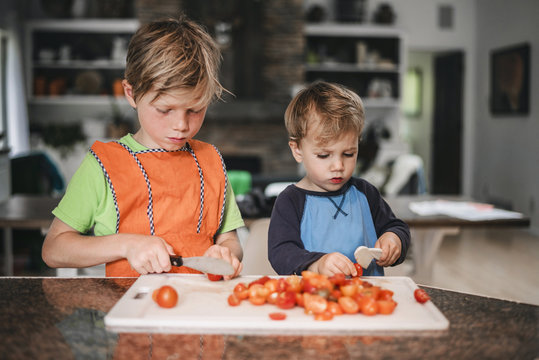 Two boys chopping tomatoes in the kitchen