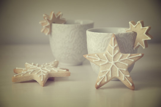 Two cups and star shaped cookies decorated with icing on a table
