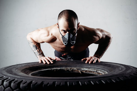 Portrait of a man wearing an elevation mask leaning on a tyre