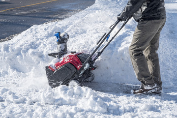 Man Removing Snow with a Snowblower on a Sunny Day