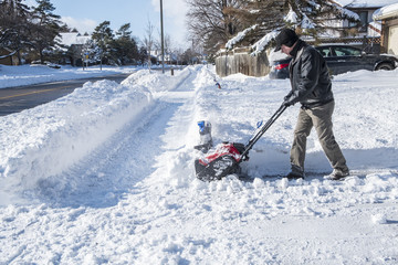 Man Removing Snow with a Snowblower on a Sunny Day