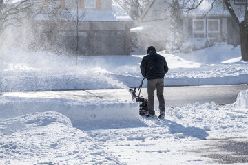 Man Removing Snow with a Snowblower on a Sunny Day