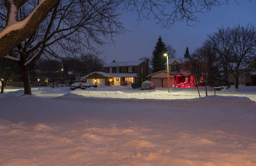 Scenic Suburban Neighborhood Houses Lit Up with Christmas Lights and Covered with Snow