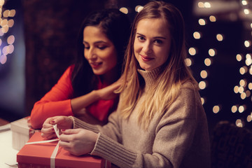 Two adolescent women going through the menue  in a fancy restaurant, while drinking a glass of red wine and laughing and talking, maybe gossiping