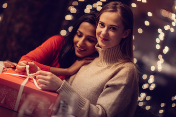 Two adolescent women going through the menue  in a fancy restaurant, while drinking a glass of red wine and laughing and talking, maybe gossiping