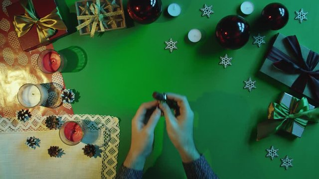 Top down view of man unwrapping candy and throwing wrapper on New Year decorated table with chroma key