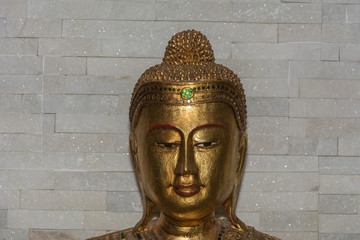 Buddha statue in gold vor steinmauer