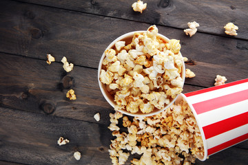 Paper cup in red and white with popcorn on wooden background